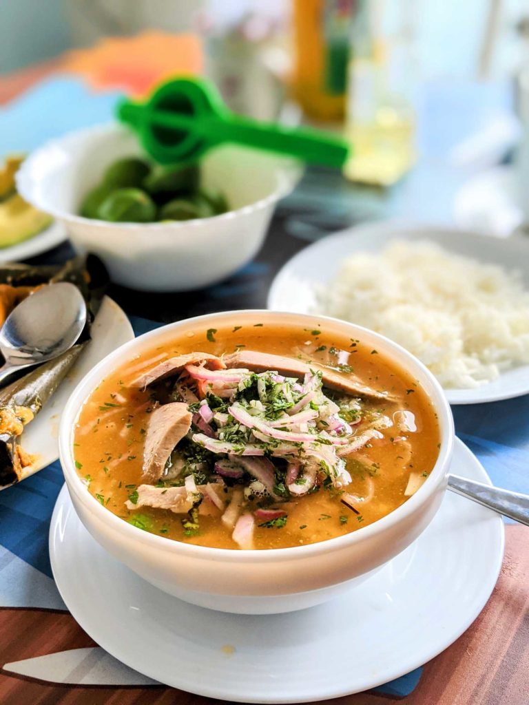Traditional Ecuadorian soup encebollado de pescado on table with garnishes