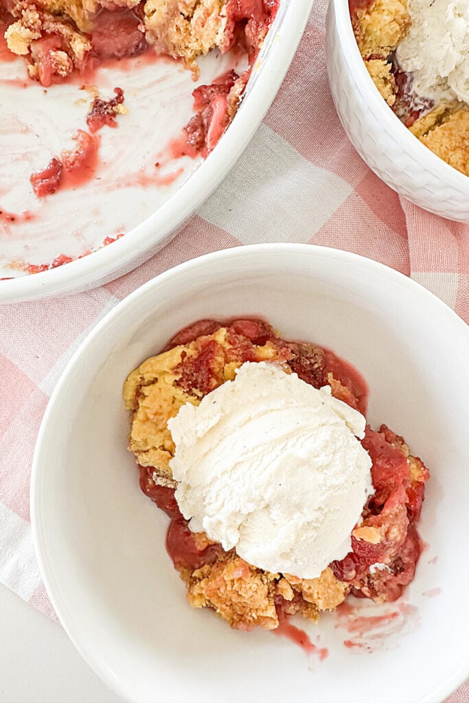 strawberry cobbler in a bowl with vanilla ice cream.